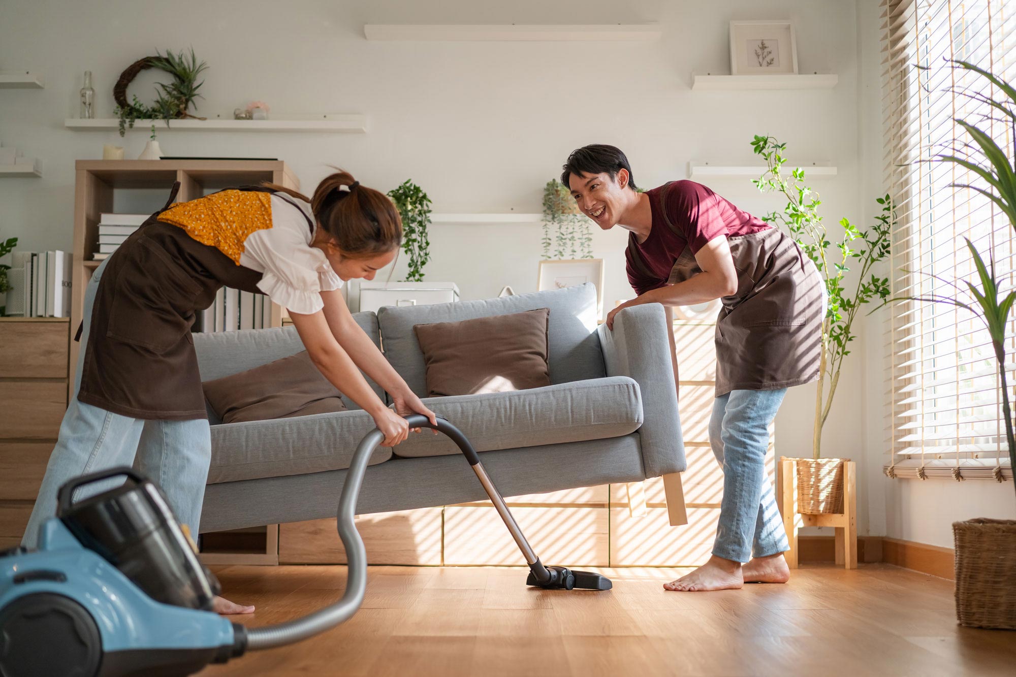 Två städare som städar under en soffa